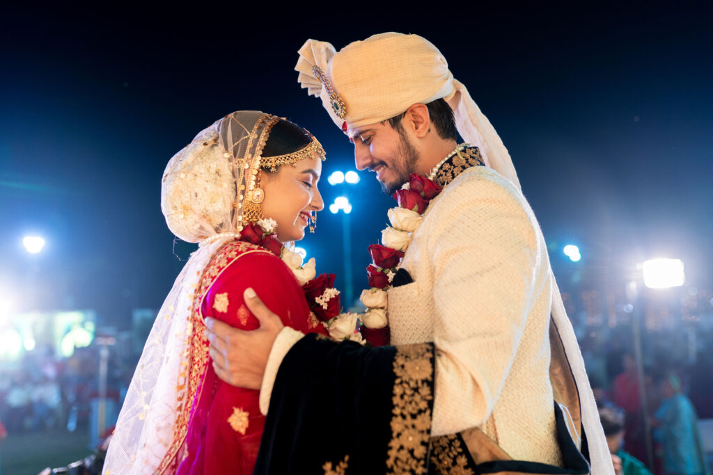 groom in white, bride in red and pink 